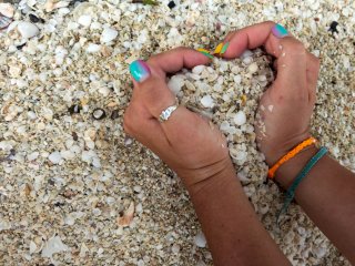 Two hands making a heart in the sand