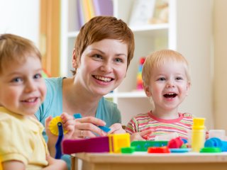 Smiling woman playing with two children in a daycare setting
